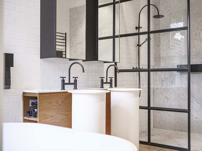 Bathroom with glass shower enclosure and dual sinks with gooseneck faucets